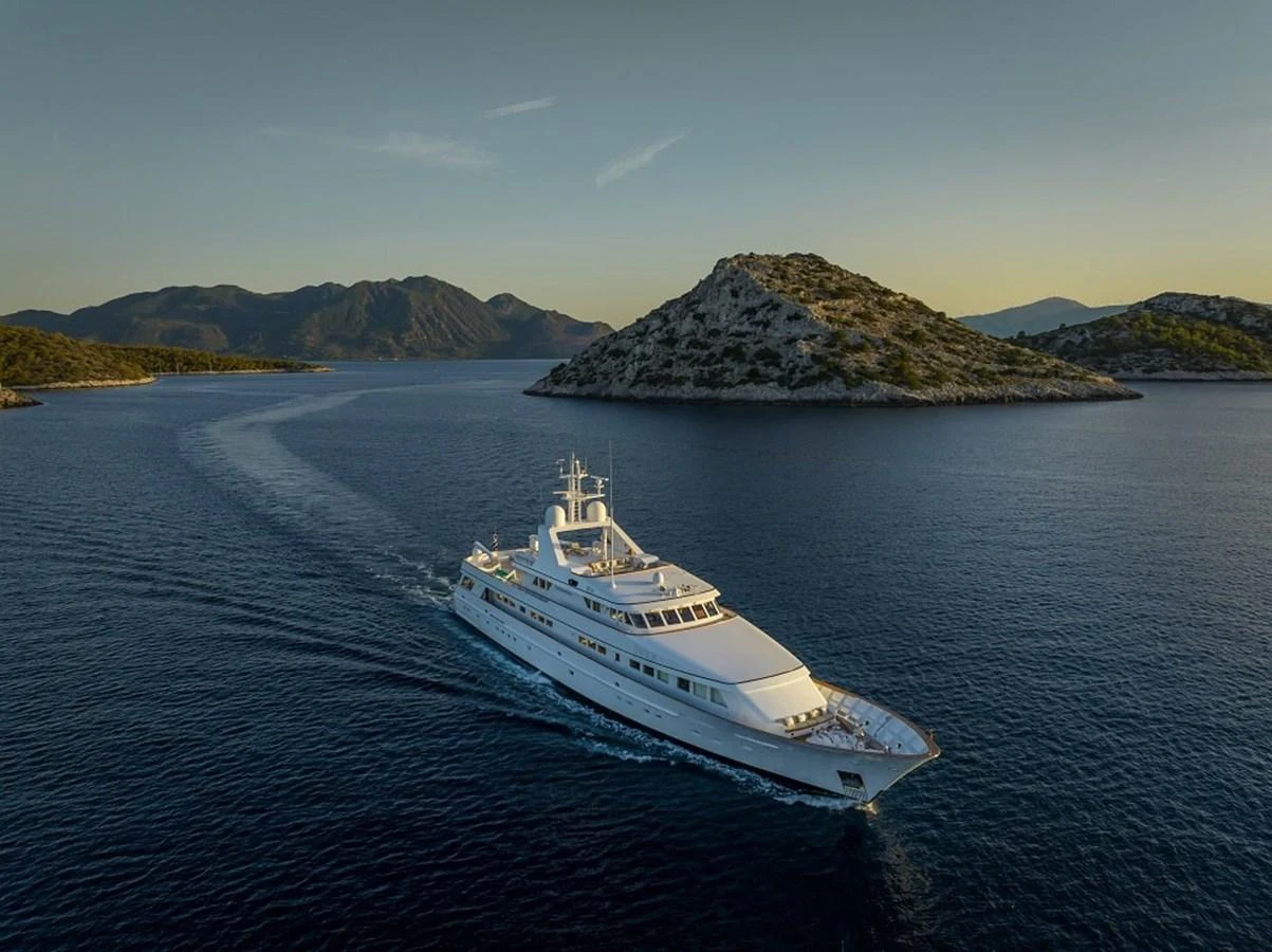 A luxurious yacht cruises through serene waters with picturesque islands in the background. aboard KASSANDRA Yacht for Sale