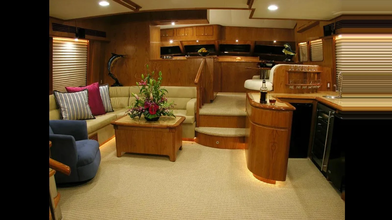 The yacht's salon features a cozy seating area with plush cushions, a wooden coffee table, and a well-equipped bar. aboard MIKELSON 75 SPORTFISHER Yacht for Sale