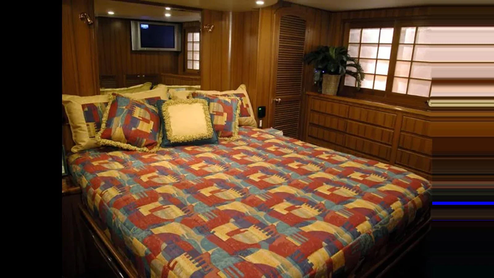 The stateroom features a large bed with colorful bedding and wood-paneled walls. aboard MIKELSON 75 SPORTFISHER Yacht for Sale