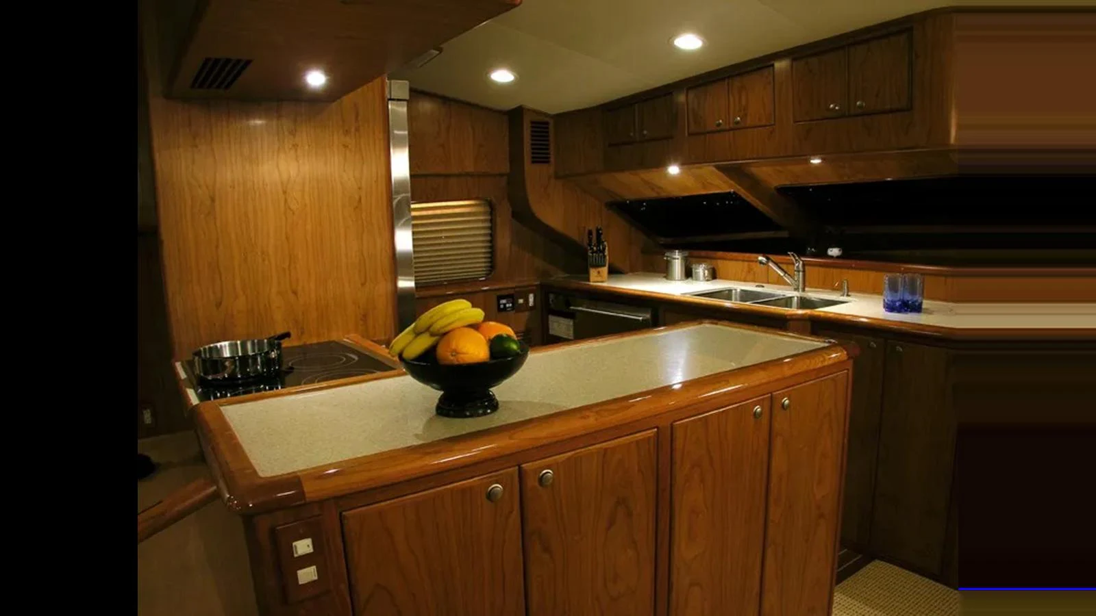 The yacht's galley features warm wood cabinetry and modern appliances, creating a cozy and functional space for meal preparation. aboard MIKELSON 75 SPORTFISHER Yacht for Sale
