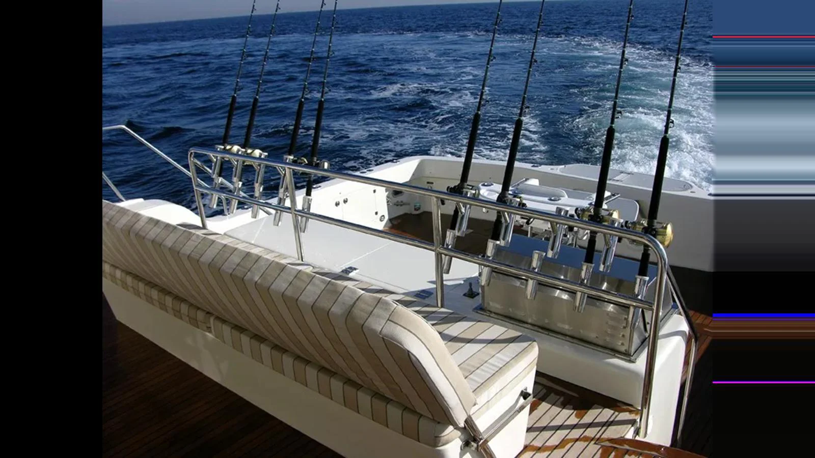 The aft deck features a well-equipped fishing setup with multiple rods and a comfortable seating area. aboard MIKELSON 75 SPORTFISHER Yacht for Sale