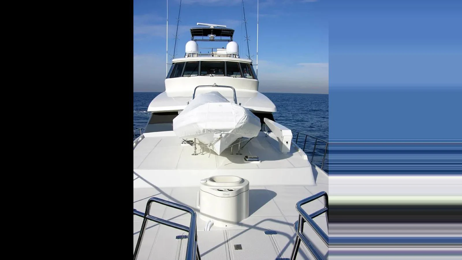 The yacht's bow is showcased with a tender securely positioned on the deck, set against a serene ocean backdrop. aboard MIKELSON 75 SPORTFISHER Yacht for Sale