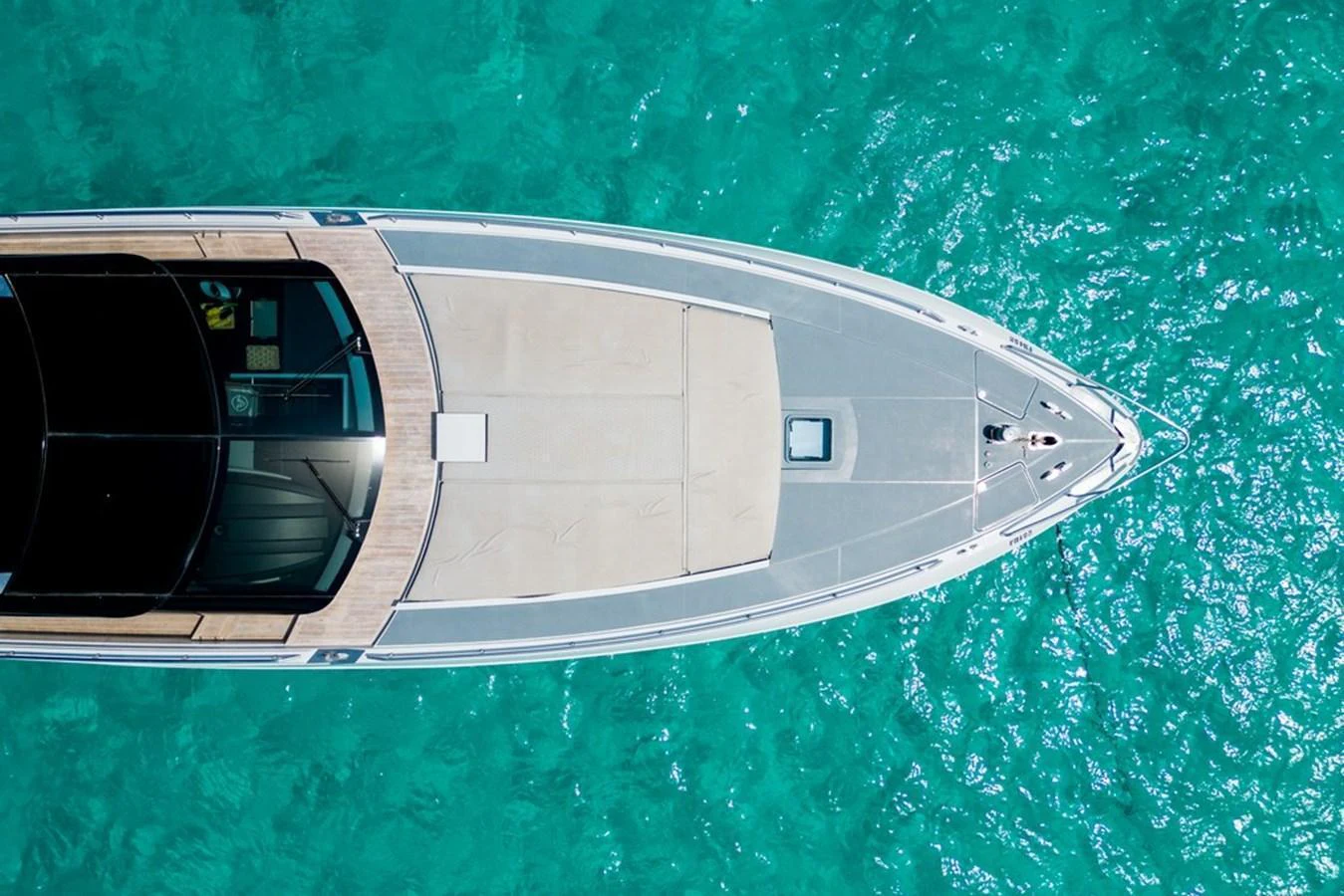 A sleek yacht glides over crystal-clear turquoise waters, showcasing its elegant foredeck. aboard BAIA 70 Yacht for Sale