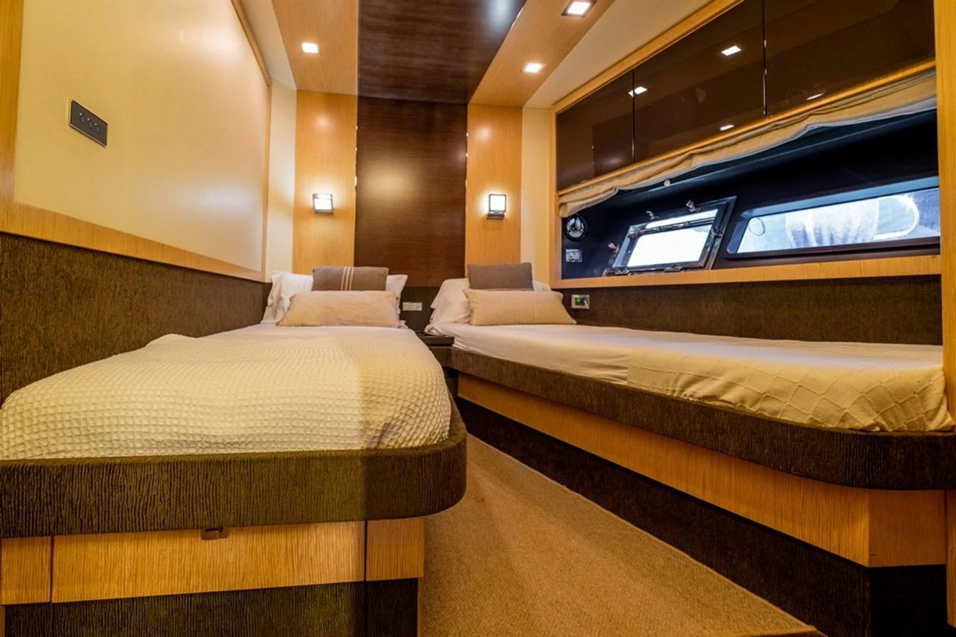 The twin stateroom offers a cozy and elegant sleeping area with two single beds and modern lighting. aboard BAIA 70 Yacht for Sale