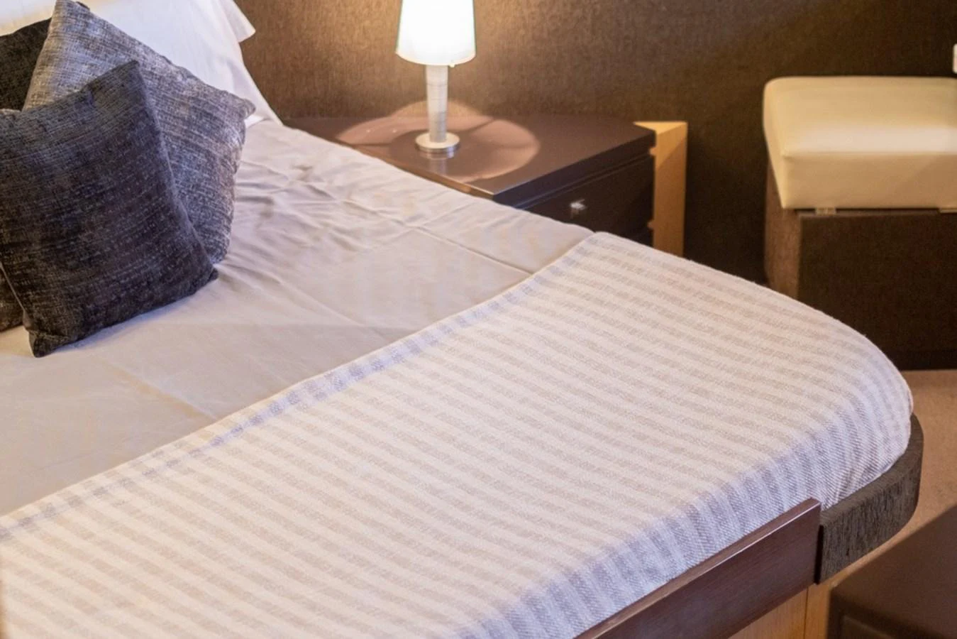 The stateroom features a cozy bed with plush pillows and a bedside lamp, creating a warm and inviting atmosphere. aboard BAIA 70 Yacht for Sale