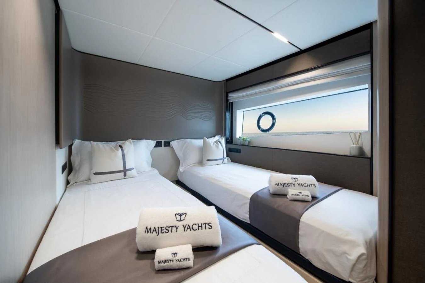 The guest stateroom features twin beds with elegant linens and a large window offering a serene ocean view. aboard TOPAZ Yacht for Sale