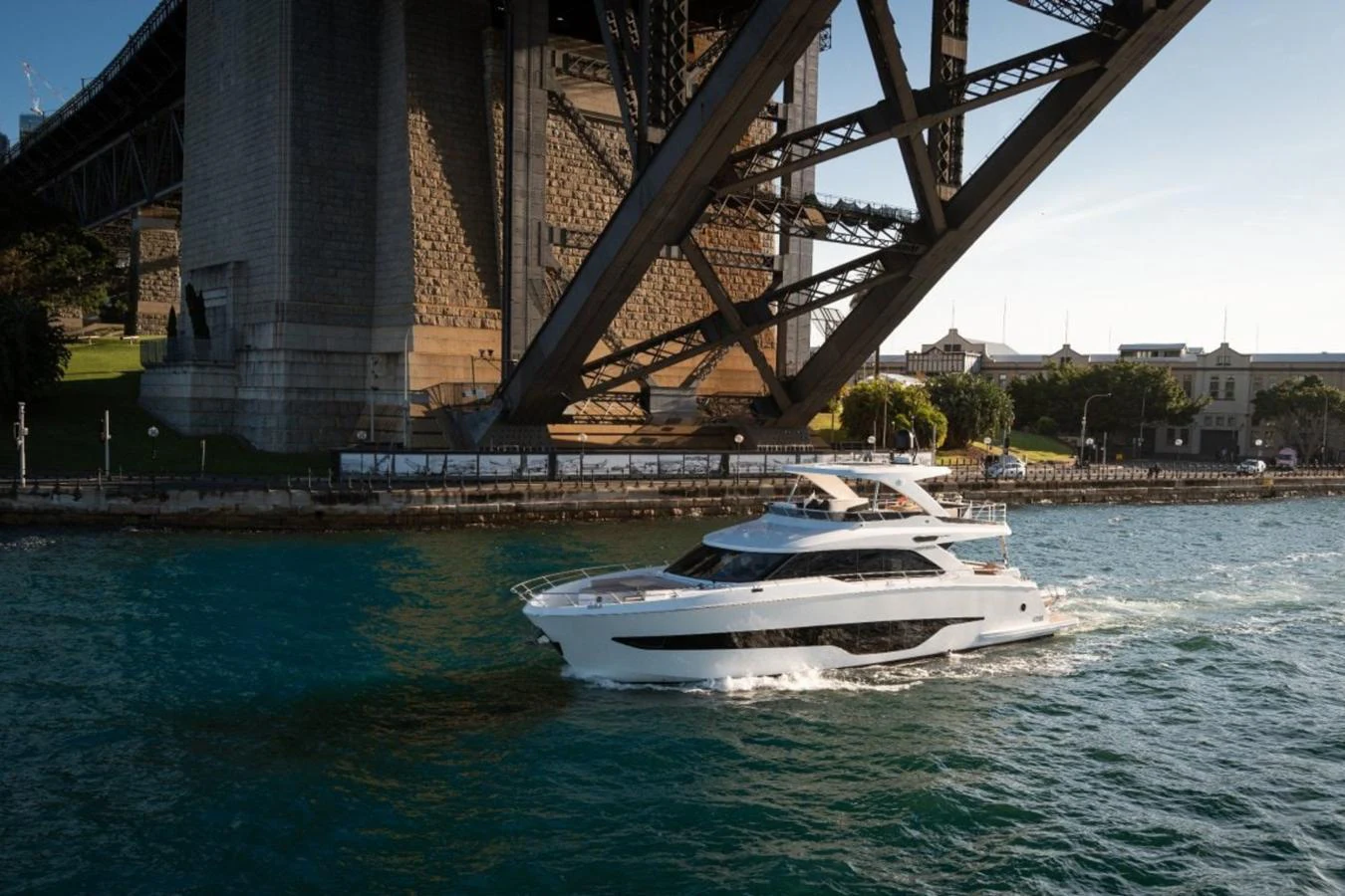 A sleek yacht cruises gracefully under a large bridge, showcasing its elegant design and modern features. aboard TOPAZ Yacht for Sale