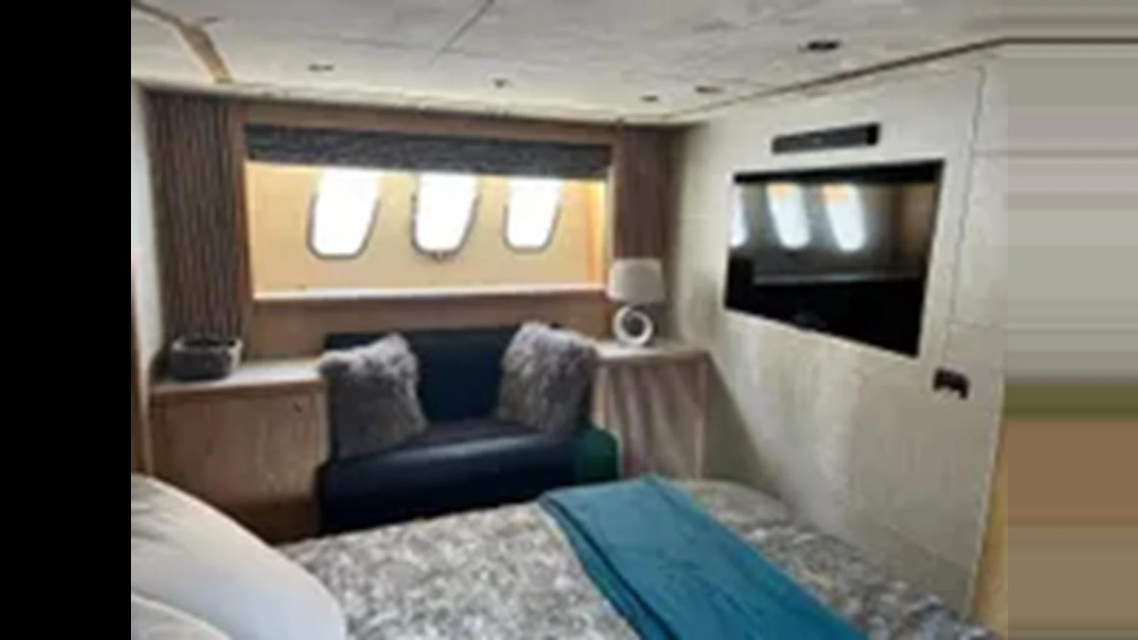 A cozy stateroom with a large bed, seating area, and ample natural light from the windows. aboard 2006 SUNSEEKER PREDATOR 82 Yacht for Sale