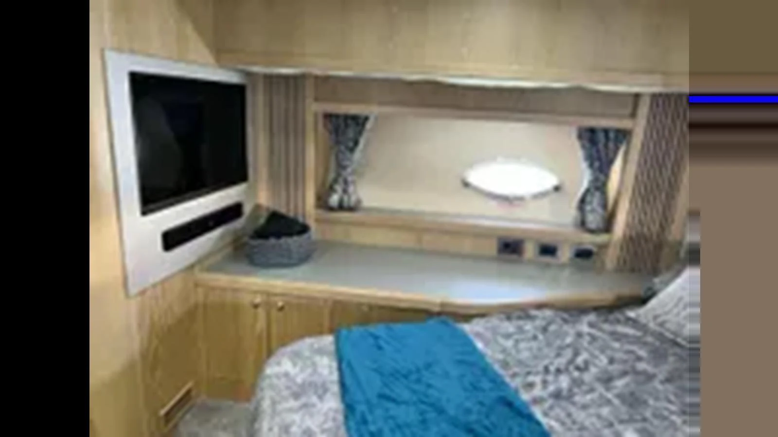 A cozy yacht cabin featuring a comfortable bed, a television, and a window with curtains. aboard 2006 SUNSEEKER PREDATOR 82 Yacht for Sale