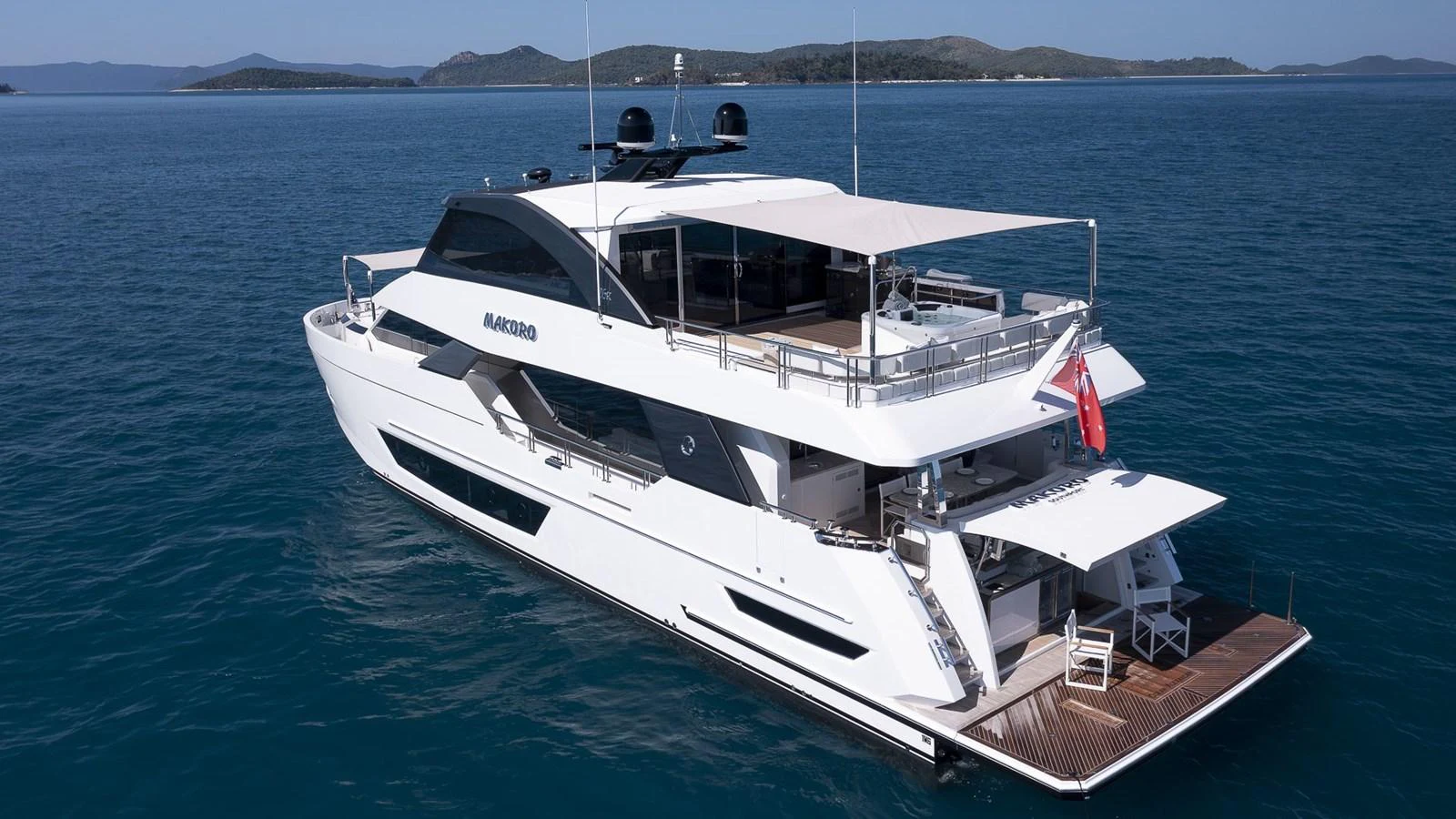 A sleek, modern yacht cruising on calm blue waters with a spacious aft deck and flybridge. aboard MAKORO Yacht for Sale