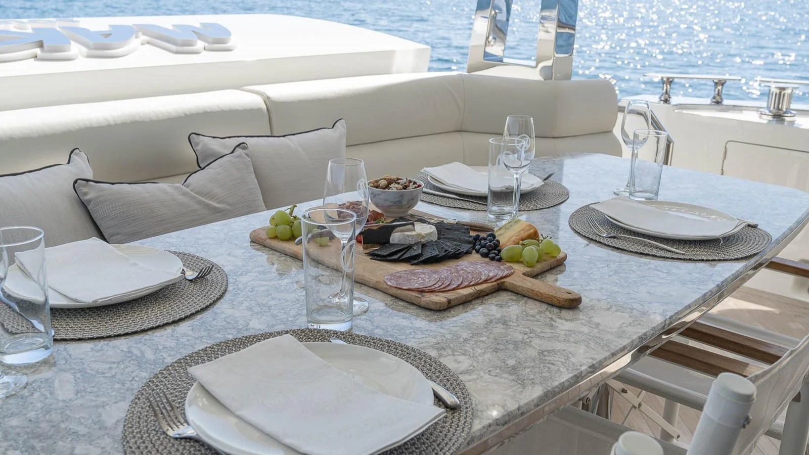 An elegant outdoor dining area set with a marble table and luxurious seating, overlooking the water. aboard MAKORO Yacht for Sale