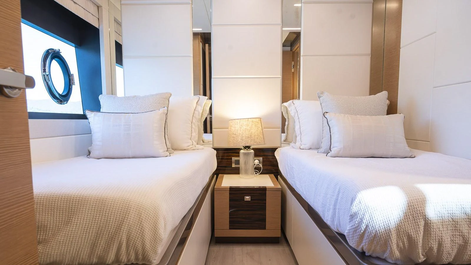 The guest stateroom features twin beds with plush bedding and a stylish bedside lamp. aboard MAKORO Yacht for Sale