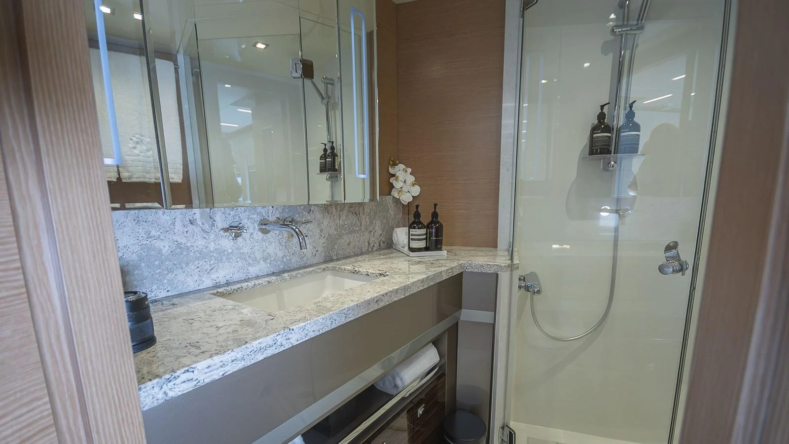 The yacht's bathroom features a sleek design with a marble countertop and a glass-enclosed shower. aboard MAKORO Yacht for Sale