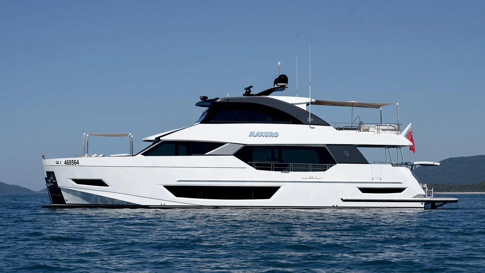 A sleek and modern yacht glides gracefully on calm waters under a clear blue sky. aboard MAKORO Yacht for Sale