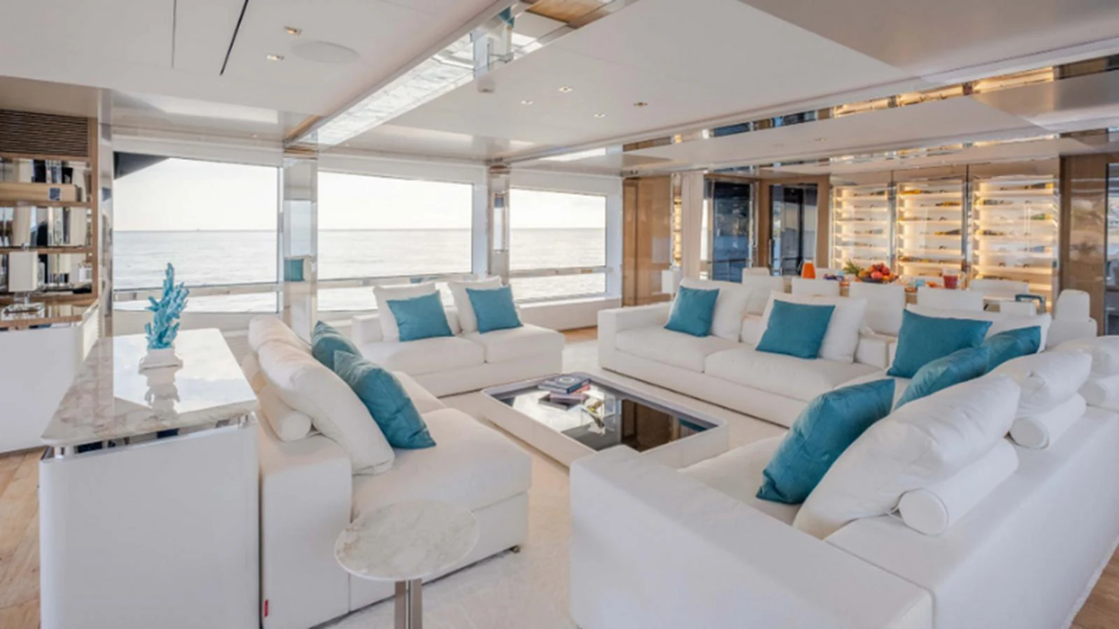 The spacious salon features plush white seating with blue accent pillows, offering a luxurious and inviting atmosphere. aboard NEW Yacht for Sale