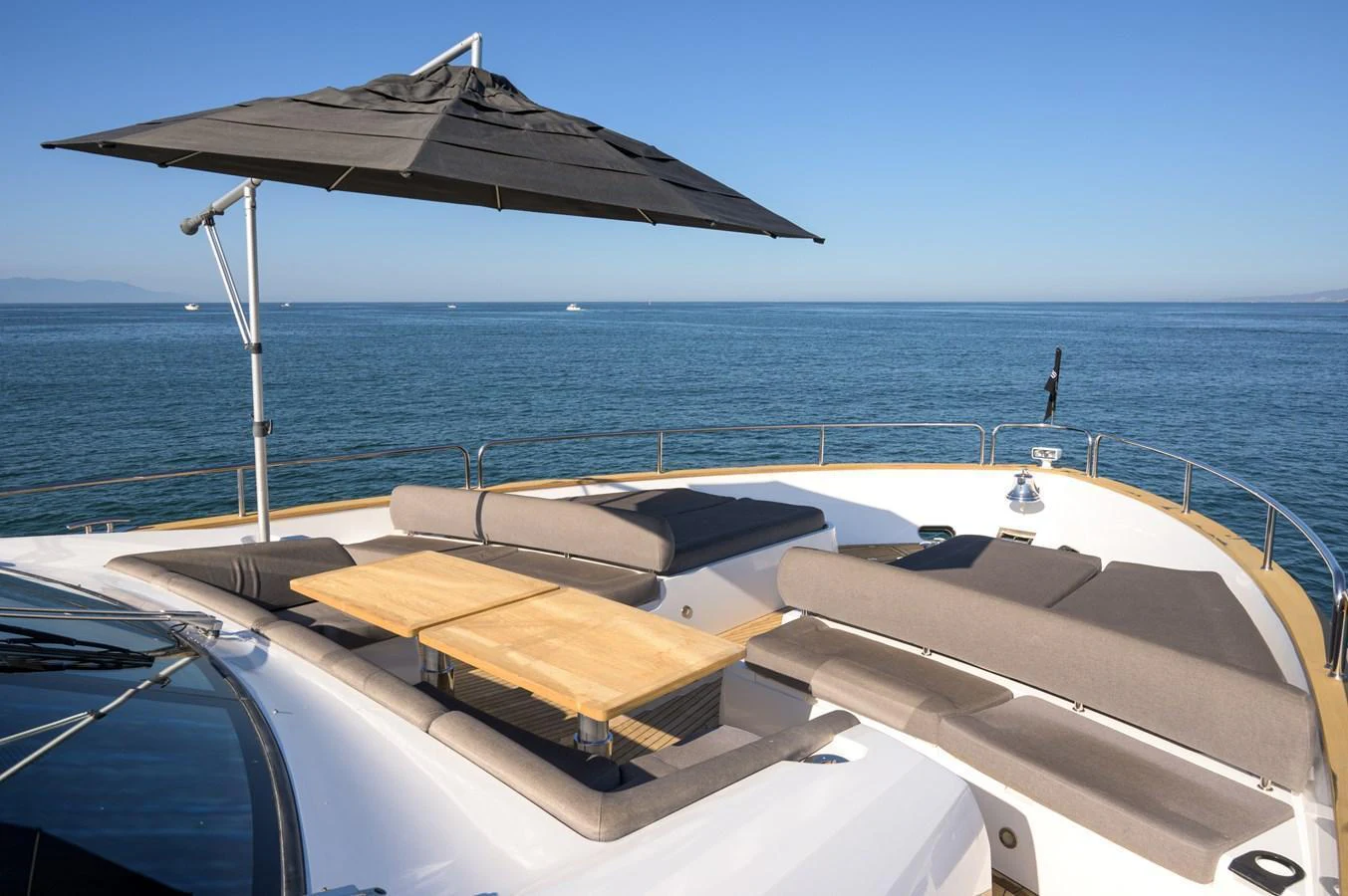 The sundeck features a comfortable lounging area with a wooden table and a large umbrella for shade. aboard EBRA Yacht for Sale