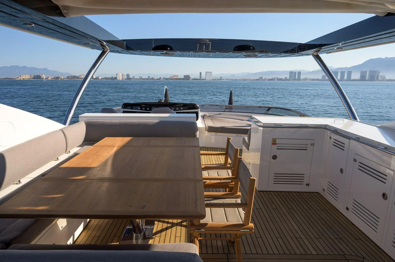 The aft deck features a spacious dining area with a wooden table and chairs, offering stunning views of the surrounding waters. aboard EBRA Yacht for Sale