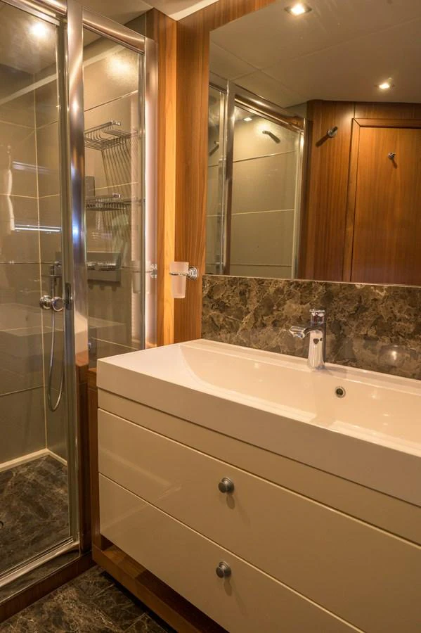 The yacht's bathroom features a sleek design with a modern sink and a glass-enclosed shower. aboard EBRA Yacht for Sale