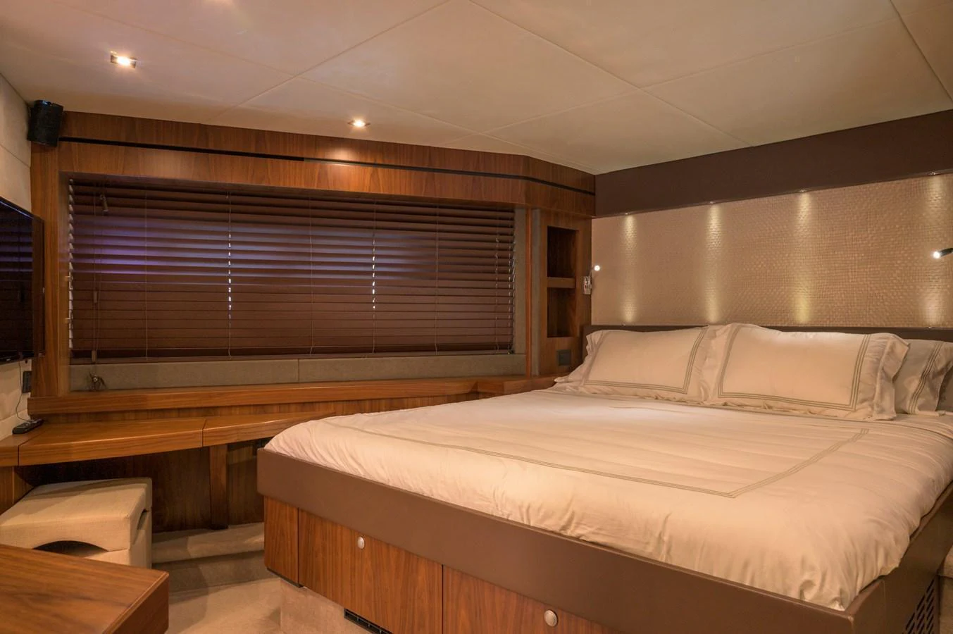 The master stateroom features a luxurious bed with elegant wood finishes and ambient lighting. aboard EBRA Yacht for Sale