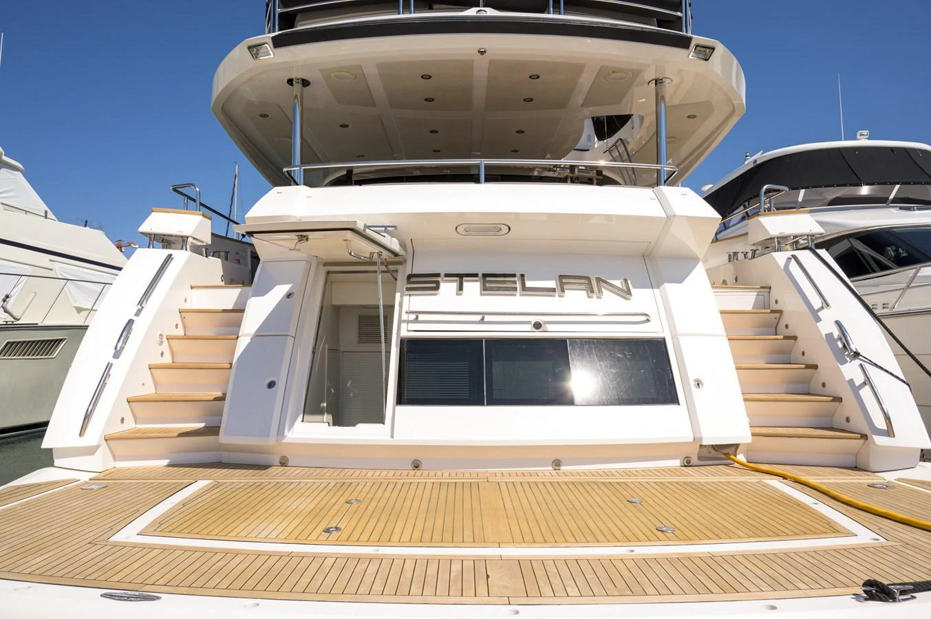 The spacious aft deck features elegant teak flooring and wide steps leading to the upper deck. aboard EBRA Yacht for Sale