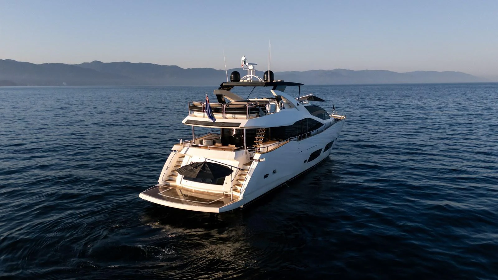 A luxurious yacht cruising on calm waters with a scenic mountain backdrop. aboard EBRA Yacht for Sale
