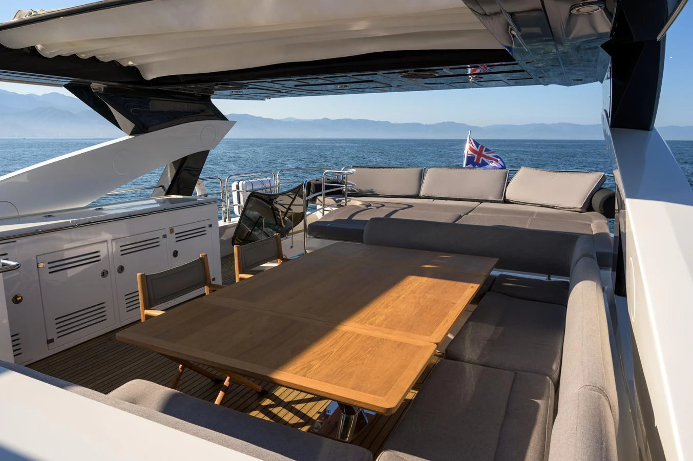 The flybridge offers a spacious seating area with a large dining table, perfect for alfresco dining with stunning sea views. aboard EBRA Yacht for Sale