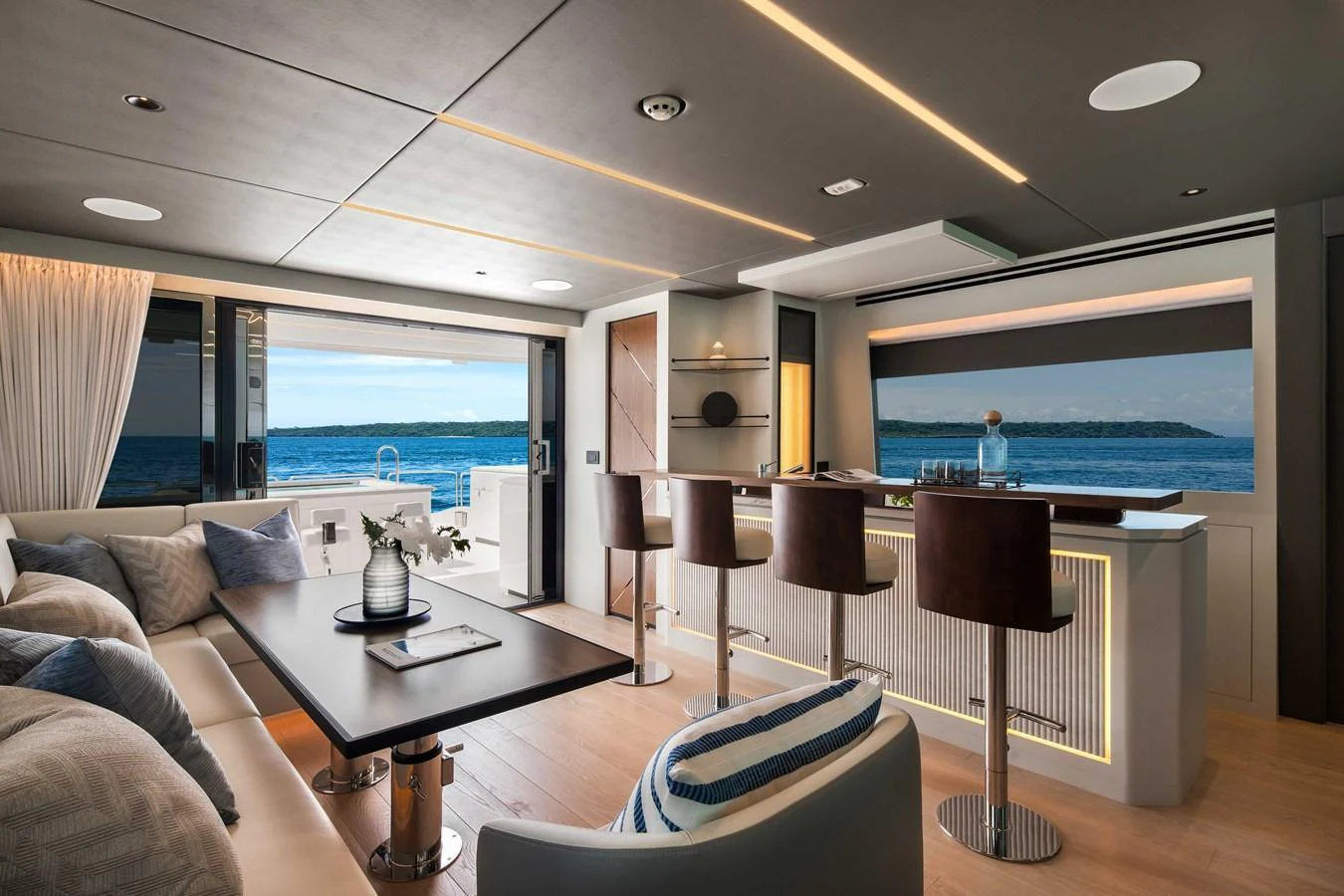 The yacht's salon offers a luxurious and modern space with a bar area and comfortable seating, complemented by stunning ocean views. aboard HORIZON FD80-617 / COMING FALL 2025 Yacht for Sale