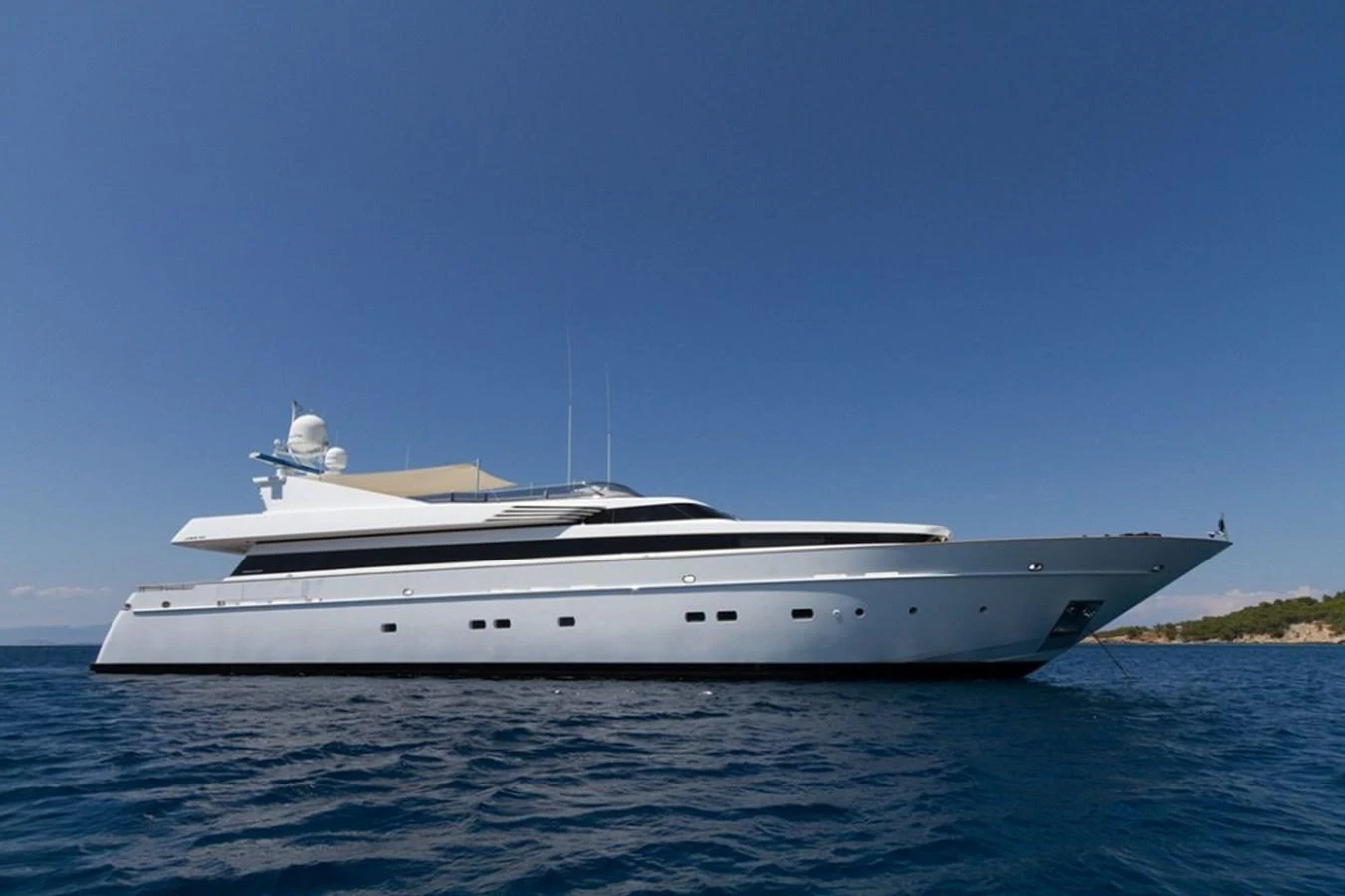 A sleek and modern yacht glides gracefully on the open water under a clear blue sky. aboard MABROUK Yacht for Sale