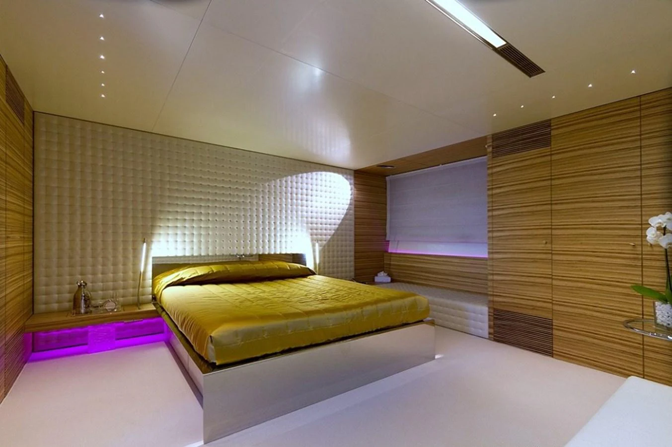 The stateroom features a luxurious bed with modern lighting and elegant wood paneling. aboard MABROUK Yacht for Sale