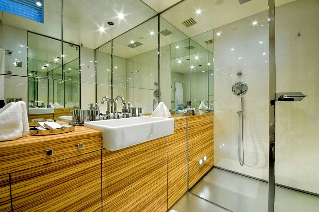 The yacht's bathroom features modern fixtures and a sleek design with ample mirrors and wood accents. aboard MABROUK Yacht for Sale