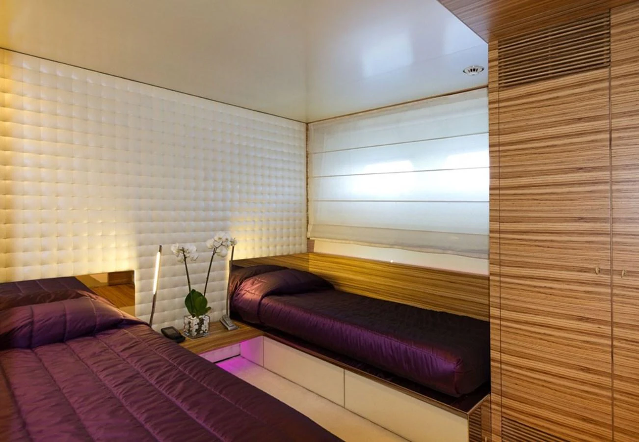 The guest stateroom features modern design with twin beds and elegant wood paneling. aboard MABROUK Yacht for Sale