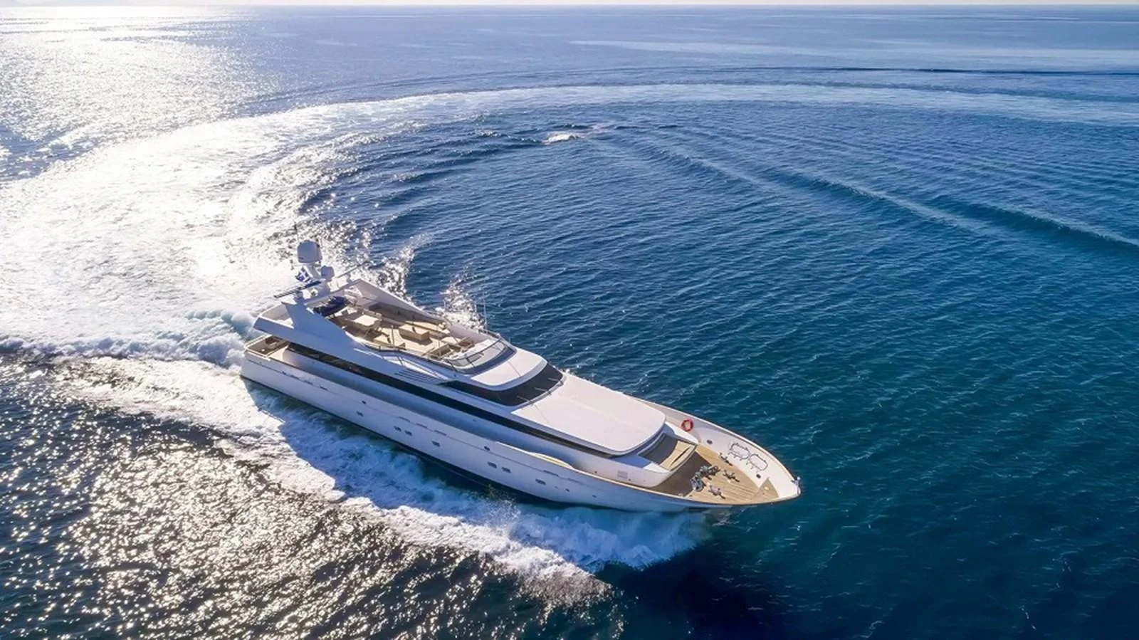 A sleek and modern yacht cruises gracefully through the open sea, leaving a trail of white foam in its wake. aboard MABROUK Yacht for Sale