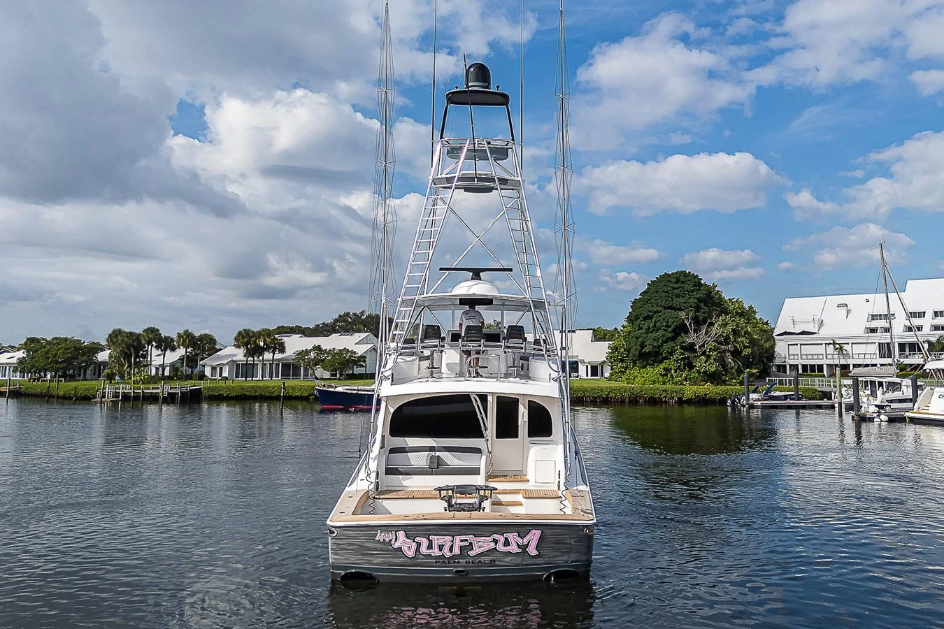 A sleek yacht is docked in a serene marina under a partly cloudy sky. aboard LADY SURFBUM Yacht for Sale