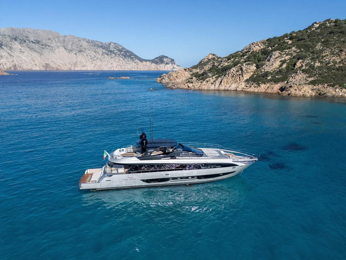 A sleek yacht cruises through clear blue waters with a stunning rocky coastline in the background. aboard FILIPPETTI F100-03 Yacht for Sale