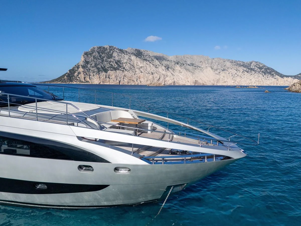 A sleek and modern yacht glides through pristine blue waters with a stunning rocky coastline in the background. aboard FILIPPETTI F100-03 Yacht for Sale