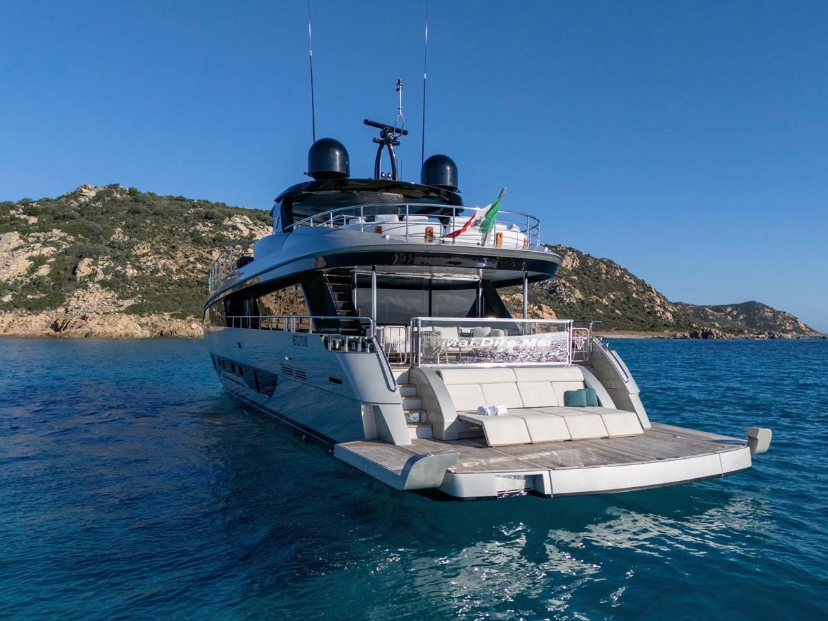 A sleek yacht anchored in clear blue waters with a scenic rocky coastline in the background. aboard FILIPPETTI F100-03 Yacht for Sale