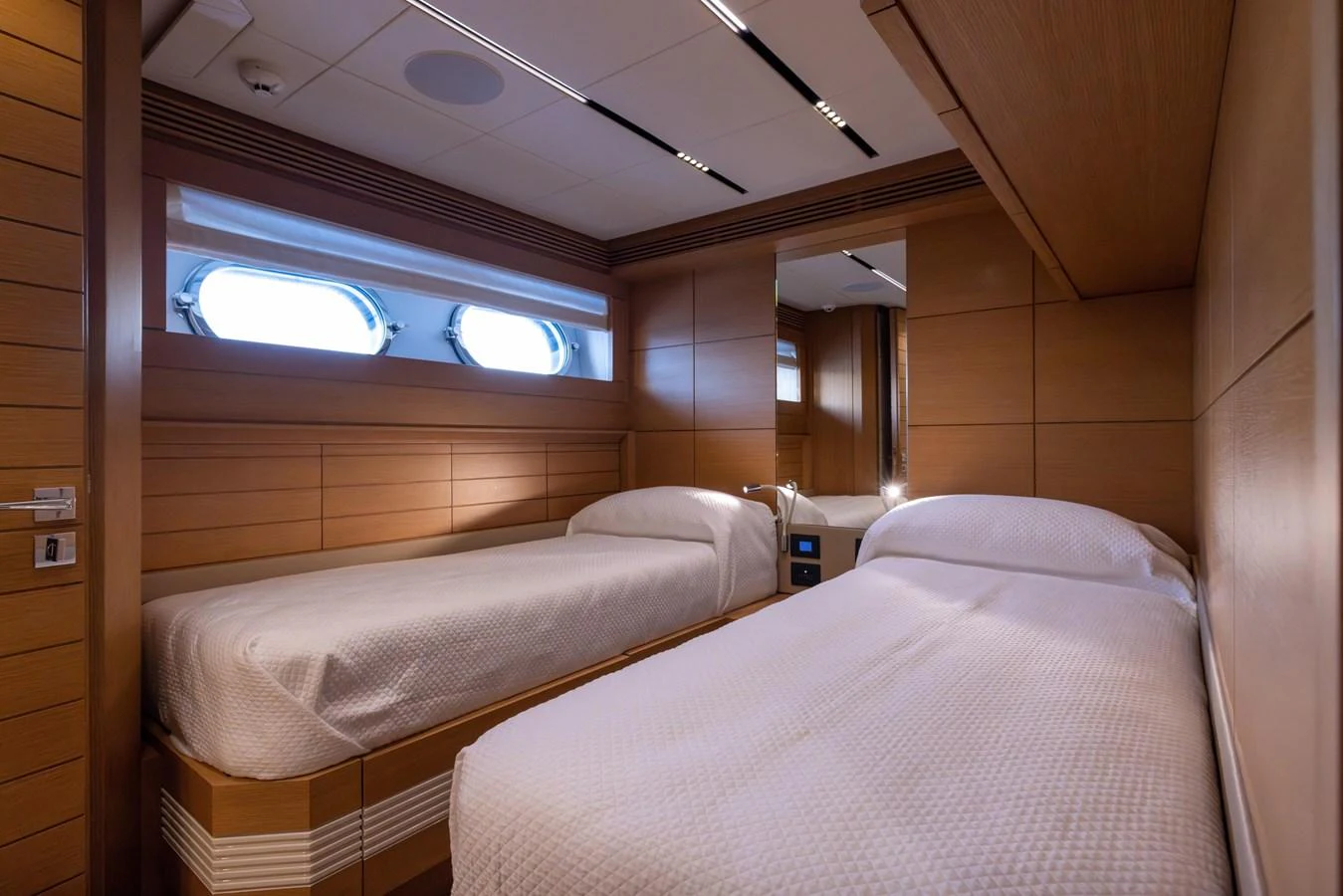 The guest stateroom features twin beds with modern wood paneling and ample natural light from the portholes. aboard FILIPPETTI F100-03 Yacht for Sale