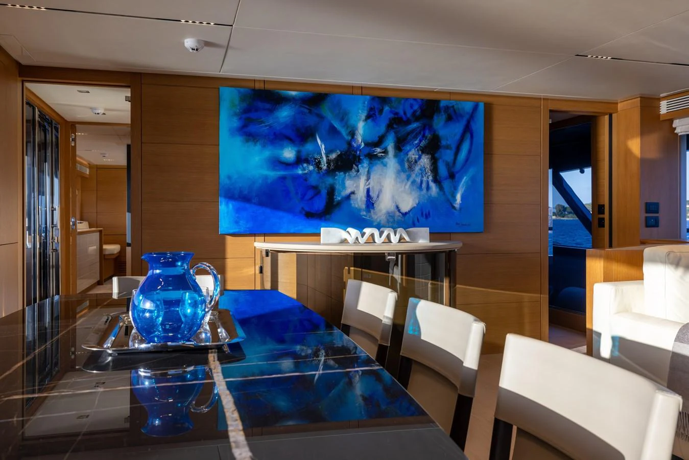 The yacht's dining area features a sleek table with a striking blue art piece on the wall, creating a modern and elegant ambiance. aboard FILIPPETTI F100-03 Yacht for Sale