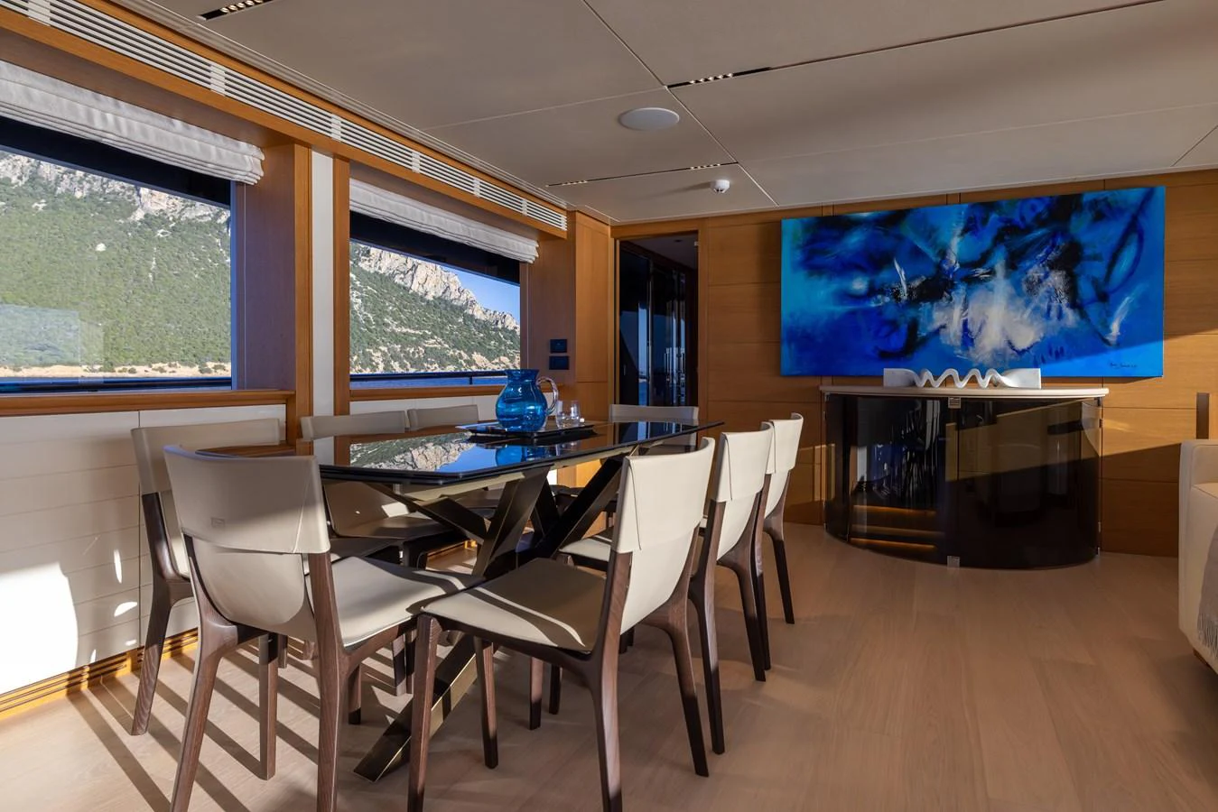 The yacht's dining area features a sleek glass table and modern chairs, complemented by large windows with scenic views. aboard FILIPPETTI F100-03 Yacht for Sale
