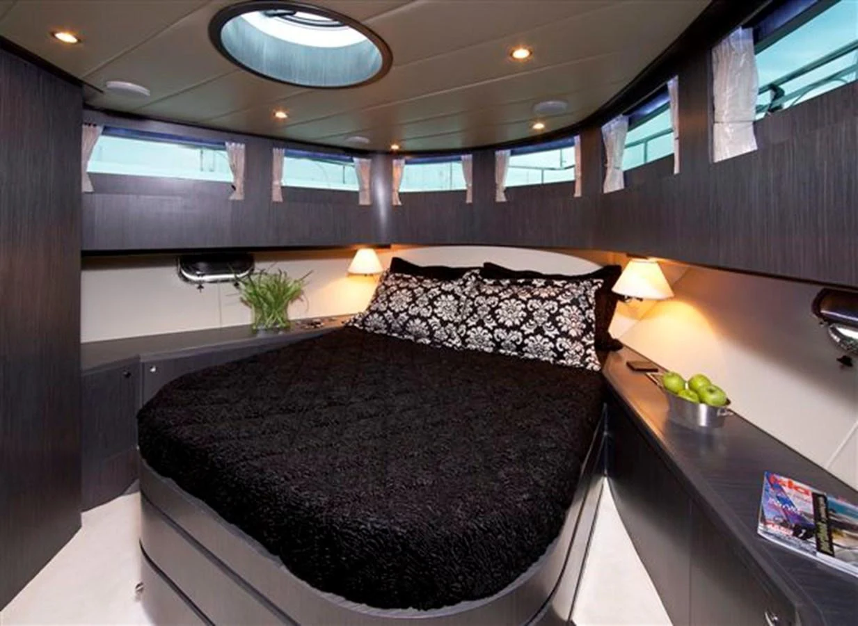A cozy stateroom with a double bed, modern decor, and ample natural light from the surrounding windows. aboard JOHNSON 83’ SKYLOUNGE W/FISHING COCKPIT Yacht for Sale
