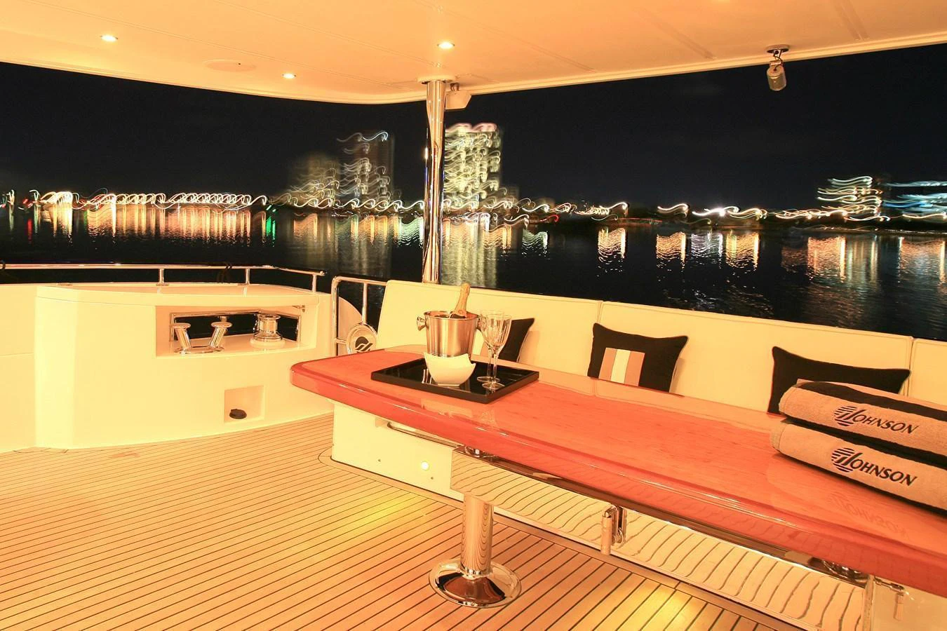 The aft deck offers a luxurious space for evening relaxation with a stunning cityscape view. aboard JOHNSON 83’ SKYLOUNGE W/FISHING COCKPIT Yacht for Sale