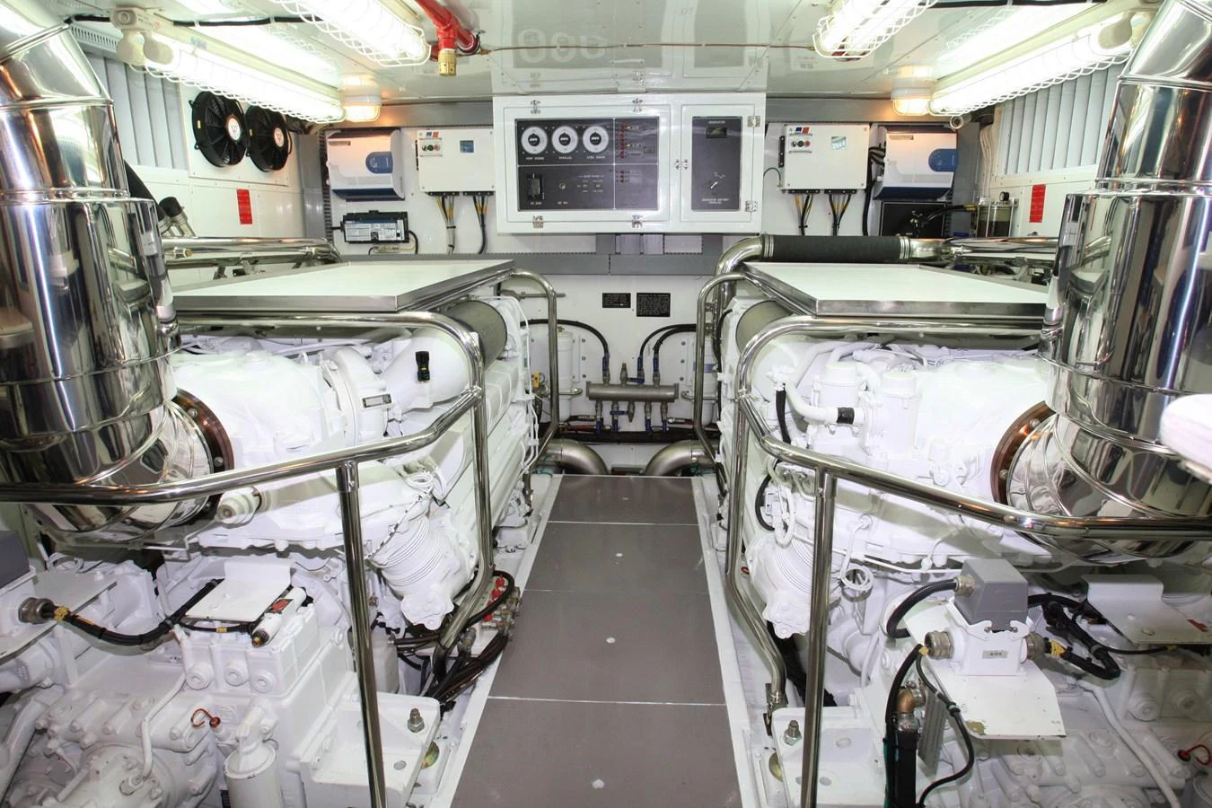 The image showcases a pristine engine room with dual engines and polished metal surfaces. aboard JOHNSON 83’ SKYLOUNGE W/FISHING COCKPIT Yacht for Sale