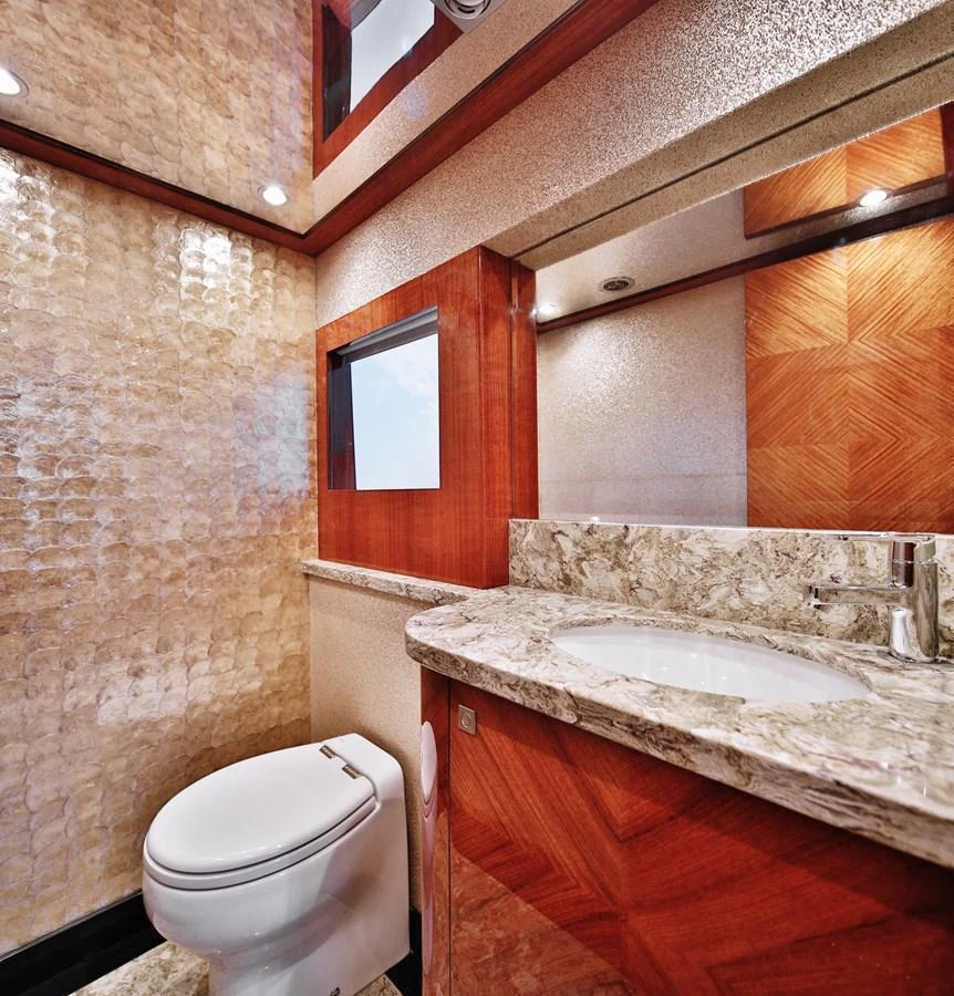 The yacht's bathroom features elegant wood paneling and a luxurious marble countertop. aboard JOHNSON 83' FLYBRIDGE W/HYDRAULIC PLATFORM Yacht for Sale