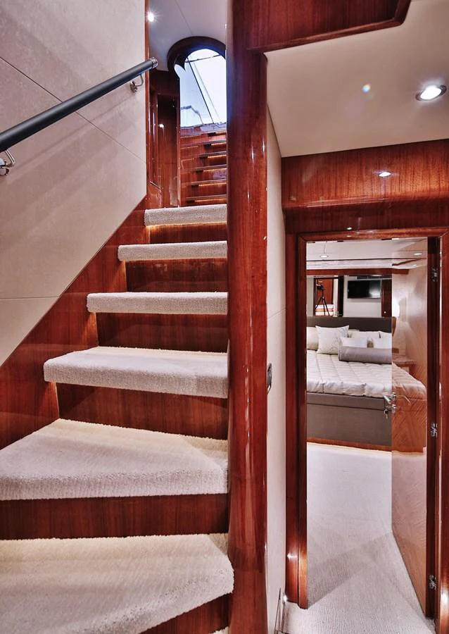 A luxurious interior staircase leads to a cozy stateroom. aboard JOHNSON 83' FLYBRIDGE W/HYDRAULIC PLATFORM Yacht for Sale