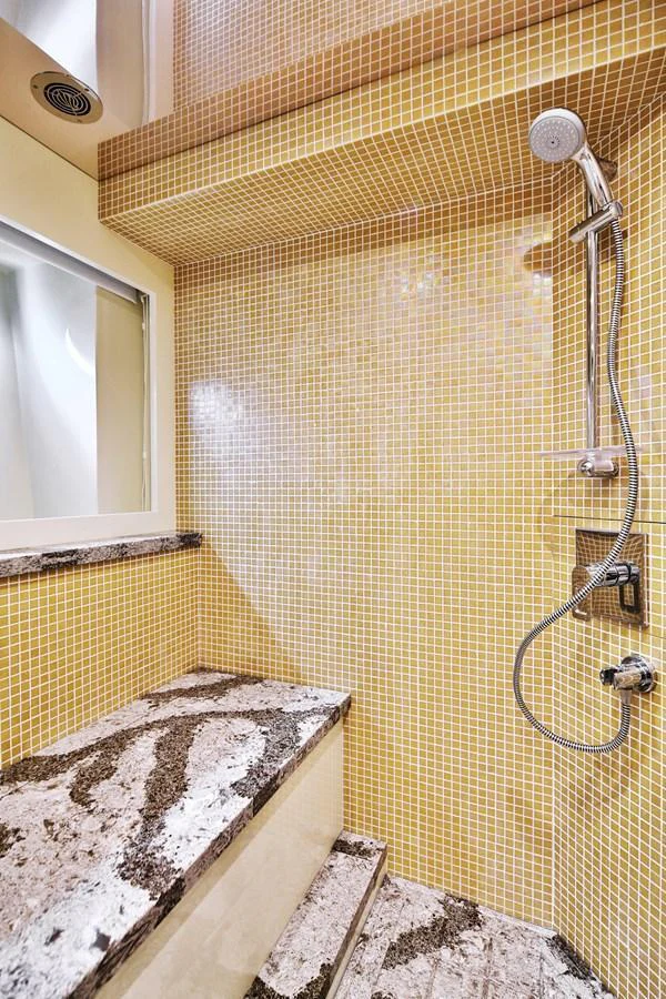 The yacht's bathroom features elegant mosaic tiles and a modern shower setup. aboard JOHNSON 83' FLYBRIDGE W/HYDRAULIC PLATFORM Yacht for Sale