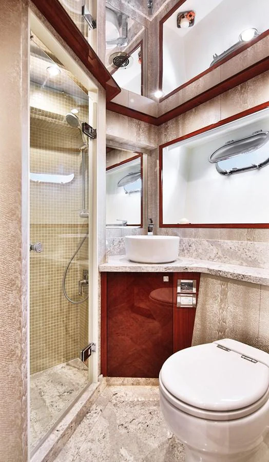 The yacht's bathroom features a modern design with a glass-enclosed shower, sleek fixtures, and elegant marble surfaces. aboard JOHNSON 83' FLYBRIDGE W/HYDRAULIC PLATFORM Yacht for Sale
