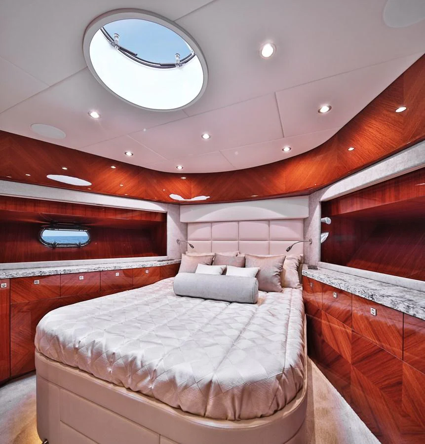 The stateroom features a luxurious bed with elegant wood paneling and ample natural light from a circular skylight. aboard JOHNSON 83' FLYBRIDGE W/HYDRAULIC PLATFORM Yacht for Sale