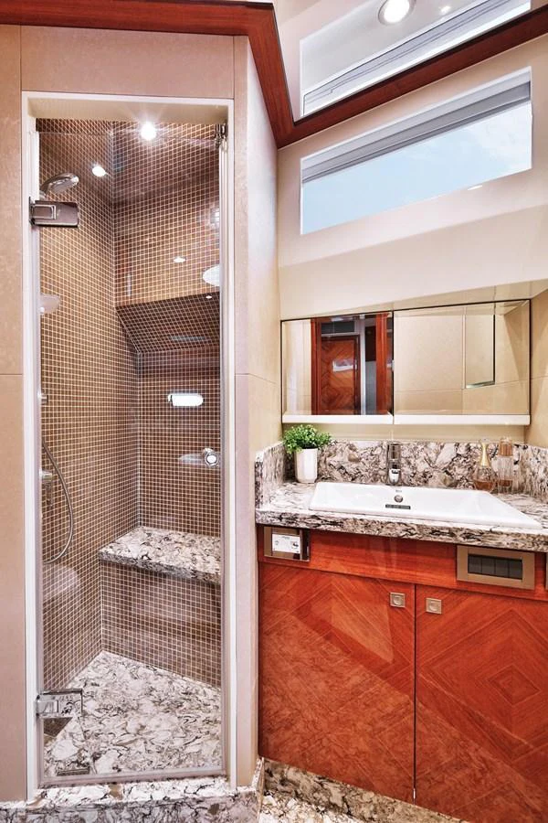 The yacht's bathroom features a luxurious shower and elegant marble countertops. aboard JOHNSON 83' FLYBRIDGE W/HYDRAULIC PLATFORM Yacht for Sale