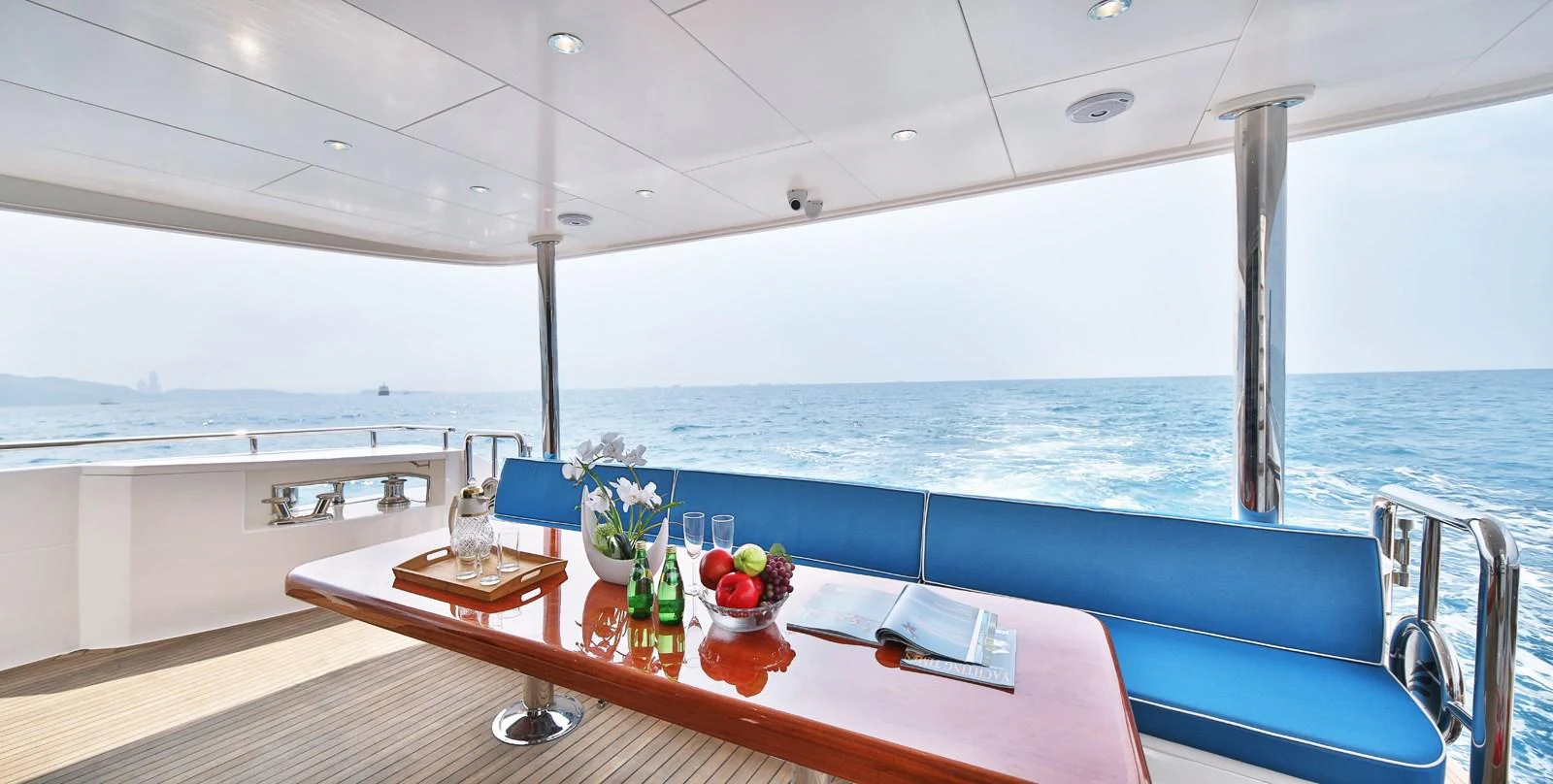 The aft deck features a stylish dining area with a wooden table and comfortable seating, offering stunning ocean views. aboard JOHNSON 83' FLYBRIDGE W/HYDRAULIC PLATFORM Yacht for Sale