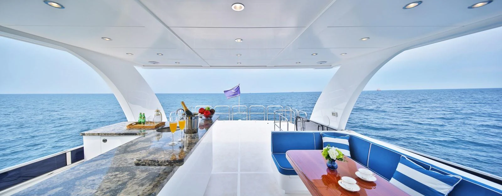 The aft deck features a luxurious outdoor dining area with a bar and stunning ocean views. aboard JOHNSON 83' FLYBRIDGE W/HYDRAULIC PLATFORM Yacht for Sale